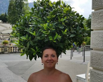 Portrait of smiling woman standing below tree