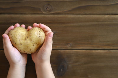 Cropped image of hand holding heart shape on table