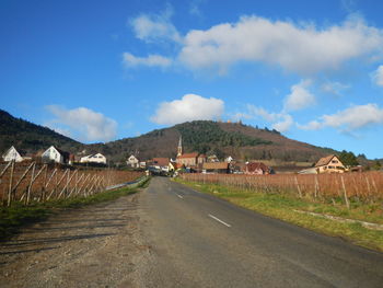 Empty road leading towards mountains against cloudy sky