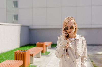 Young woman using smart phone against wall