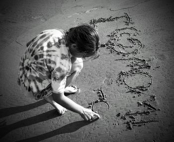 High angle view of girl scribbling on sand at beach