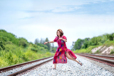 Portrait of woman with railroad tracks against sky
