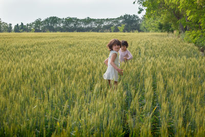 Two girls with short dark hair playing together in wheat field