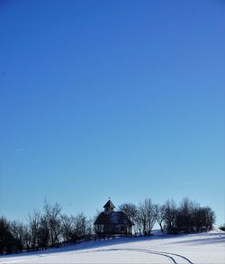 Snow covered trees against clear blue sky