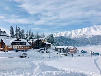 Houses on snow covered landscape against sky