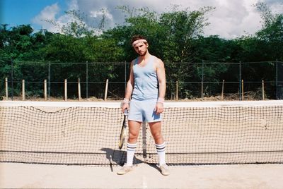 Young man in tennis outfit holding racket in court