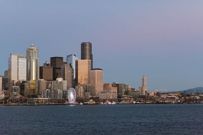 Sea by cityscape against clear sky