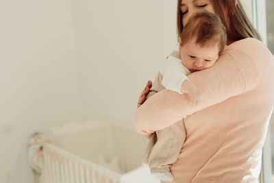 Mother carrying cute daughter at home