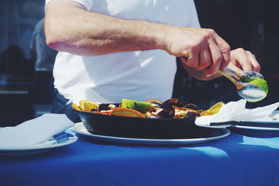 Midsection of man eating food at table