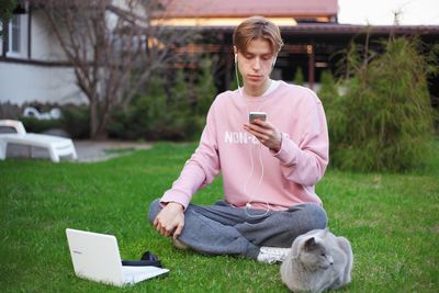 Young man using mobile phone while sitting on grass