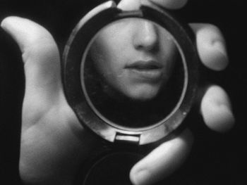 Cropped image of hand holding with woman biting lip reflection against black background