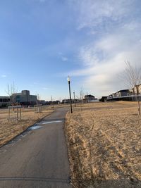 Empty road by city against sky