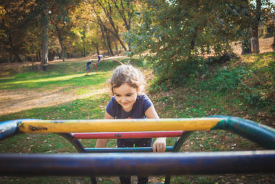 Happy girl playing on jungle gym in park