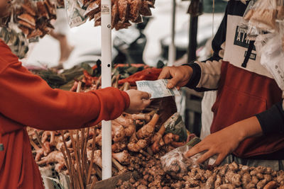 Hands holding vegetables for sale at market stall