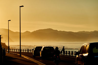 Cars on street against sky during sunrise