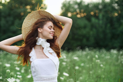 Young woman standing against plants