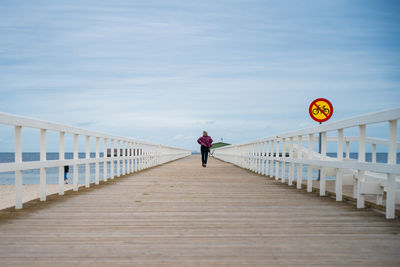 Rear view of man walking on footbridge