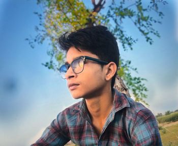 Portrait of young man looking away against sky