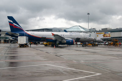 Airplane on airport runway against sky