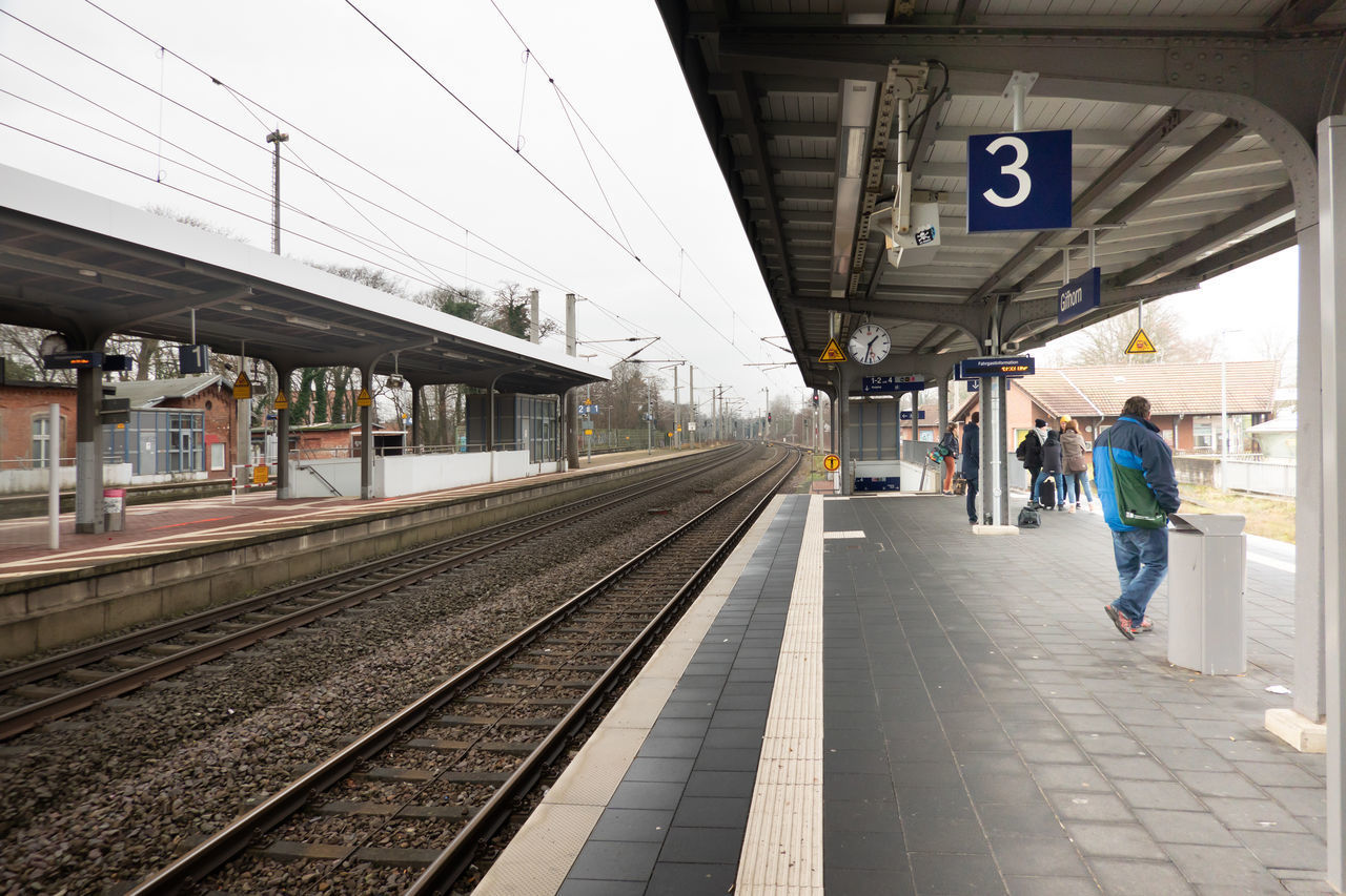 REAR VIEW OF PEOPLE ON RAILROAD STATION