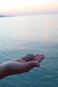 Close-up of hand holding sea against sky