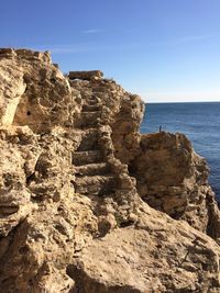 Rock formation on beach against clear blue sky