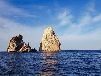 Rock formations in sea against blue sky