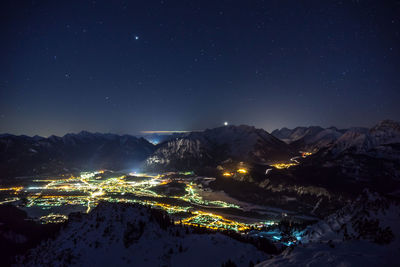 Aerial view of illuminated snowcapped mountains against sky at night
