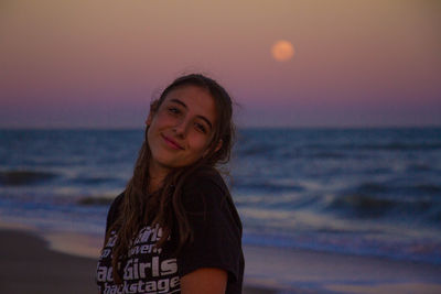 Portrait of beautiful woman on beach against sky during sunset