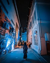 People on street amidst buildings in city at night