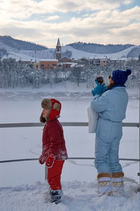 Rear view of women on snowcapped mountain against sky