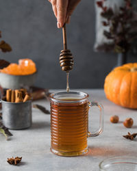 Woman adds honey to fresh hot tea on grey stone table