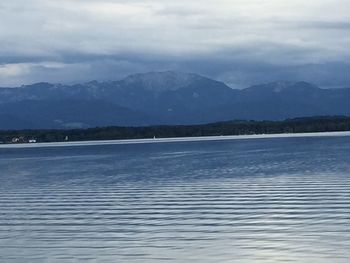 Scenic view of lake and mountains against cloudy sky