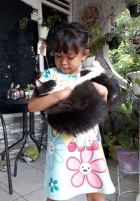Portrait of cute girl holding blue while sitting on chair