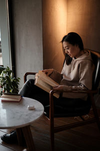 Young woman using laptop while sitting on table