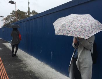 Rear view of woman with umbrella standing against the sky