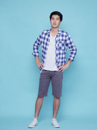 Portrait of young man standing against blue background
