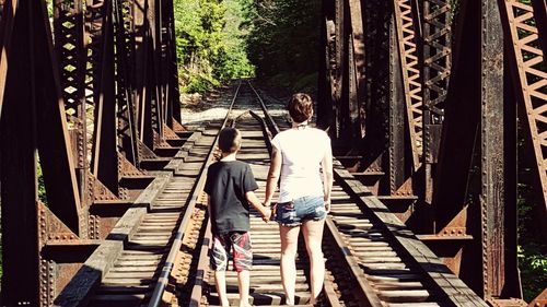 Rear view of people walking on footbridge