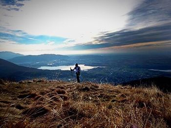 Rear view of man standing on mountain against sky