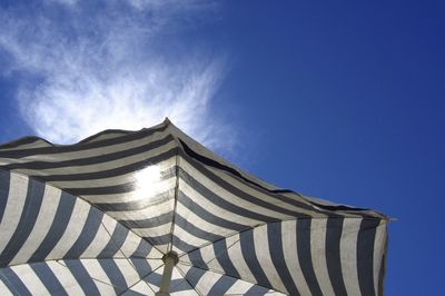 Low angle view of parasol against blue sky