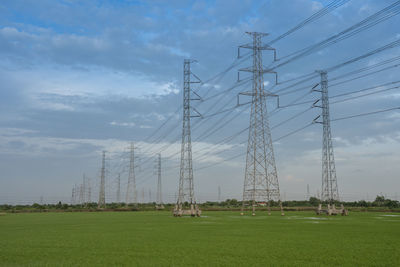 Electricity pylon on field against sky