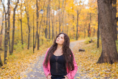 Young woman standing in forest during autumn