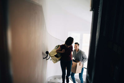 High angle view of couple carrying bag and box while climbing up steps