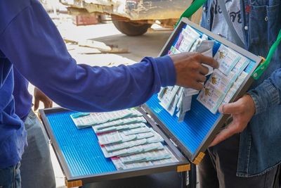 Midsection of man buying lottery tickets from vendor