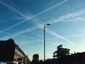 Low angle view of vapor trails against blue sky