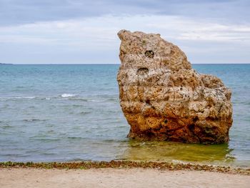 Rock formation on beach against sky