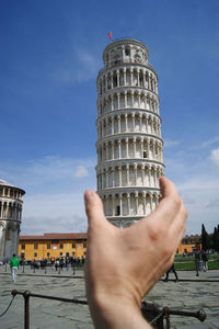 Optical illusion of cropped hand holding leaning tower of pisa