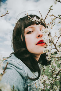 Close-up portrait of woman by plants against sky