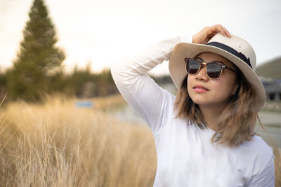 Portrait of woman wearing sunglasses standing on field