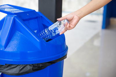 Cropped hand of person cleaning garbage bin